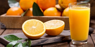 Pomerančový džus vedle rozkrojeného pomeranče