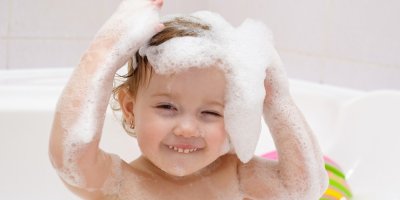 Dítě s pěnou na hlavě se koupe