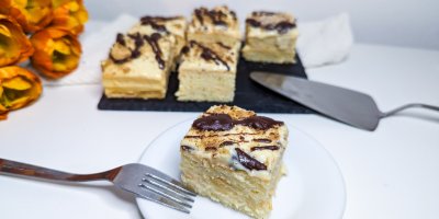 1 kousek buchty Orgasmus na bílém talíři, v pozadí na černém prkénku dalších 5 kousků buchty