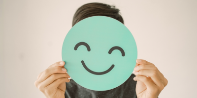 Muž drží před obličejem smajlík