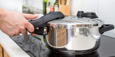 Mužské ruce manipulují s tlakovým hrncem na varné desce