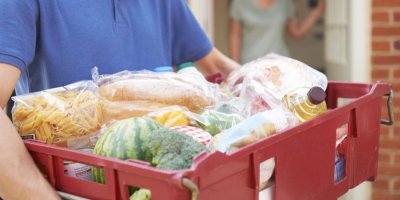 Kurýr drží bedýnku s nákupem