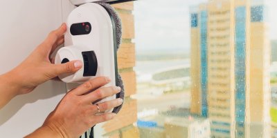 Člověk přikládá robotický čistič na okno