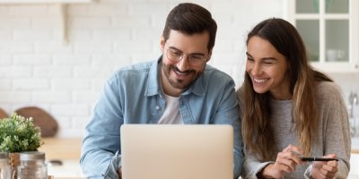 Mladý pár se usmívá a kouká do notebooku