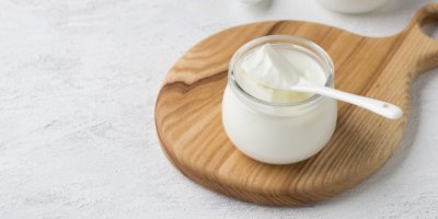 Domácí jogurt se lžičkou na dřevěném prkénku