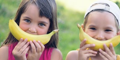 Chlapec a dívka drží banány tak, aby vypadaly jako úsměv
