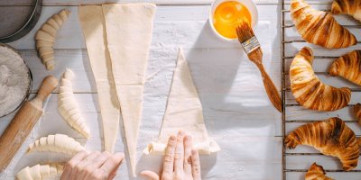 Ženské ruce, které rolují těsto na croissanty