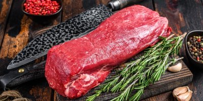 Hovězí svíčková, servírovaná na dřevěném prkénku, vedle snítky rozmarýnu