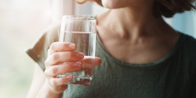 Sklenice s vodou, kterou drží osoba v rukou
