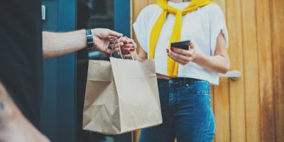 Žena přebírá jídlo v papírové tašce