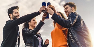 Mladí lidé si přiťukávají nápoji v plechovkách