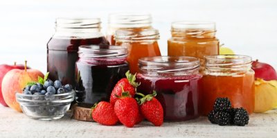 Spousta džemů ve sklenicích a ovoce okolo