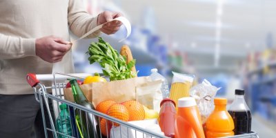 Muž má před sebou plný nákupní vozík a dívá se na účtenku