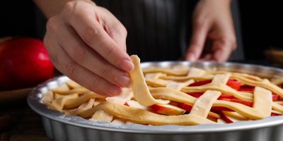 Žena, která skládá mřížku na jablečném koláči