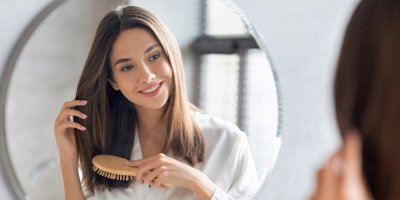 Žena si češe před zrcadlem vlasy