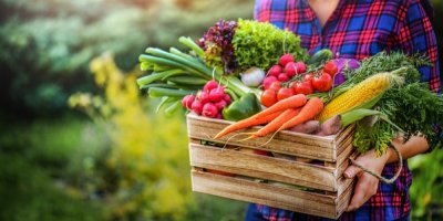 Žena drží bedýnku plnou zeleniny