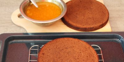 2 čokoládové korpusy Sacher dortu, vedle nich miska s meruňkovým džemem