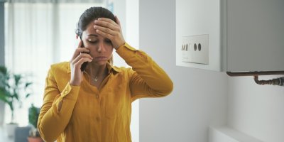 Žena se drží za hlavu a nešťastně telefonuje