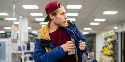 Mladík si dává v obchodě něco do bundy