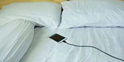Nabíjení telefonu. Telefon je v posteli