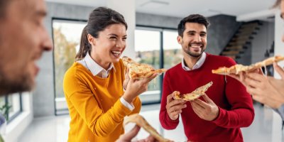 Lidé se smějí a jí pizzu