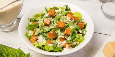 Caesar salát s dresinkem a krutony, servírovaný v bílé míse