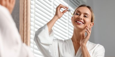 Žena si aplikuje sérum před zrcadlem