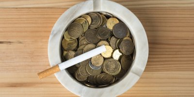 Cigareta a popelník plný mincí