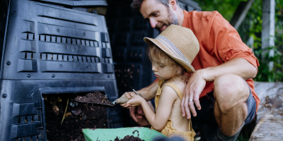 Muž s dcerou odebírají rozložený kompost z kompostéru