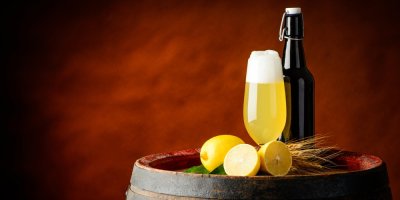 Citronový radler ve sklenici, lahev piva, citrony na sudu