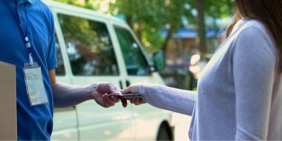 Žena předává kurýrovi za balíček hotovost