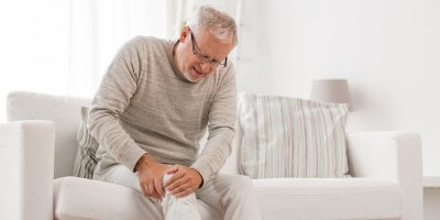 Starší muž se s bolestivým výrazem drží za koleno