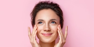 Žena se usmívá a drží se za pleť