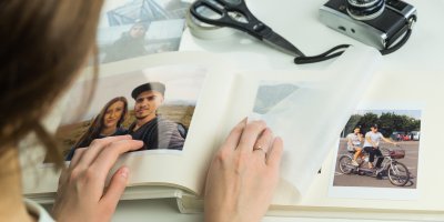 Žena připravuje fotoalbum, vedle nůžky, izolepa, fotoaparát