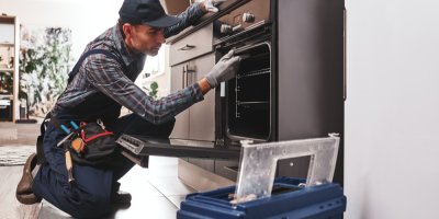 Opravář v kuchyni opravuje troubu