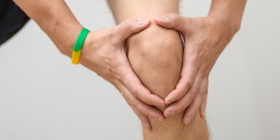 Muž se drží za koleno