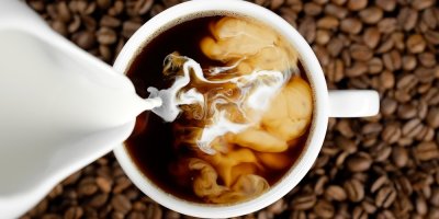 Přidávání mléka do šálku s kávou