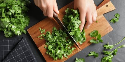 Krájení koriandru na dřevěném prkénku