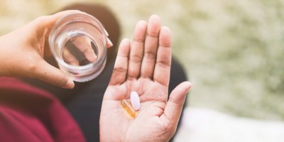 Starší žena drží v ruce doplňky stravy