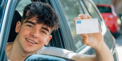 Mladý usmívající se řidič, drží řidičský průkaz