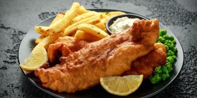 Smažená ryba s hranolky na černém talíři