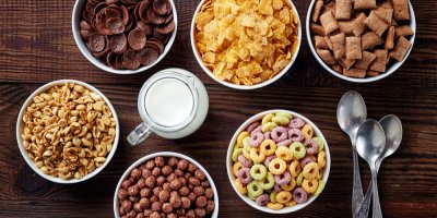 Různé druhy cereálií v miskách, džbánek s mlékem, tři lžíce