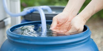 Namočené ruce v dešťové vodě v sudu