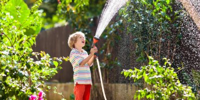 Chlapec zalévá zahradu hadicí