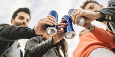 Mladí lidé si připíjejí, každý drží plechovku