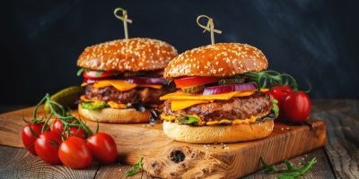 Dva hamburgery na dřevěném prkénku