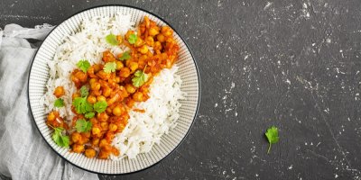 Cizrnové kari s rýží a posypané koriandrem, servírované ve zdobené misce