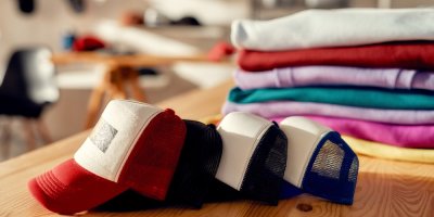 Červená, černá a modrá kšiltovka položené za sebou na stole