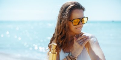Žena si roztírá opalovací krém u moře