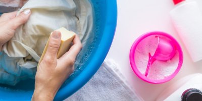 Ruce drží v ruce mýdlo a chystají se odstranit skvrnu z prádla